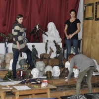 Trzy uczennice ustawiają prace uczniów ZSP w Lublinie wystawione na corocznej aukcji w szkolnej auli. Kliknięcie w miniaturkę obrazka spowoduje wyświetlenie powiększonego zdjęcia.