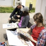 During the open-air painting, two students sit with their works. Teacher Grzegorz Tomczyk leaning over one student. Doing proofreading work. Clicking on the image thumbnail will display the enlarged photo..