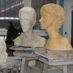 Trzy rzeźby umieszczone na kubikach w pracowni rzeźby. Dwa popiersia młodych mężczyzn, jedno młodej kobiety. Kliknięcie w miniaturkę obrazka spowoduje wyświetlenie powiększonego zdjęcia.