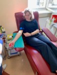 Anna Myszkowiak oddaje krew w pokoju zabiegowym. Leży na czerwonym łóżku z wyciągniętą ręką i kroplówką. Jest uśmiechnięta. Kliknięcie spowoduje wyświetlenie powiększonego zdjęcia.