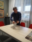 Dyr Krzysztof Dąbek stoi przy stole i zapala chanukowe świece. Kliknięcie w miniaturkę obrazka spowoduje wyświetlenie powiększonego zdjęcia.