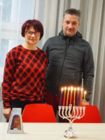 Alina Tkaczyk i Krzysztof Dąbek stoją stoją przy stole, na którym znajdują się zapalone chanukowe świece. Kliknięcie w miniaturkę obrazka spowoduje wyświetlenie powiększonego zdjęcia.