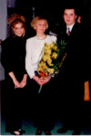 Nauczycielka z kwiatami w towarzystwie pary uczestników studniówki. Kliknięcie w miniaturkę obrazka spowoduje wyświetlenie powiększonego zdjęcia.
