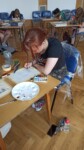 Cztery uczennice rysują i malują sceny komiksu w auli szkolnej. Kliknięcie w miniaturkę obrazka spowoduje wyświetlenie powiększonego zdjęcia.