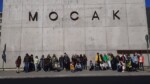 Uczniowie stoją przed galerią Mocak. Kliknięcie w miniaturkę obrazka spowoduje wyświetlenie powiększonego zdjęcia.