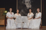 Przedstawienie w szkolnej auli. Występują 4 uczennice ubrane w białe, ślubne suknie. W tle duży obraz - portret C. K. Norwida. Kliknięcie w miniaturkę obrazka spowoduje wyświetlenie powiększonego zdjęcia.